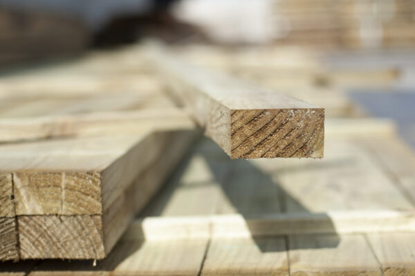 Close-up of treated timber rail with visible grain, stacked for fencing or landscaping use