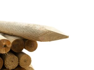 Close-up of round timber fence posts with pointed ends, stacked for fencing and landscaping use