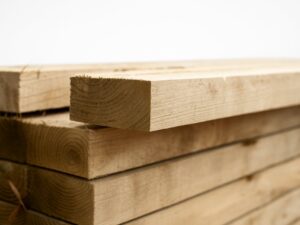 Neatly stacked treated timber sleepers on white background for landscaping use