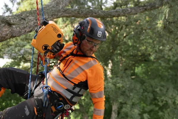 Arborist using chainsaw while wearing Husqvarna Spire Vent Helmet PPE from R & L Miller Ayrshire Glasgow Dumfries Scotland